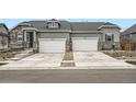 View of the exterior featuring stone accents and attached garages on a sunny day at 3492 N Buchanan Way, Aurora, CO 80019