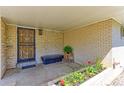 Inviting entryway with decorative door, brick accents, and potted plants near a cushioned bench seat at 3375 Zephyr Ct, Wheat Ridge, CO 80033