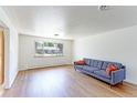 Bright living room with hardwood floors and a gray couch near a large window with outside views at 3375 Zephyr Ct, Wheat Ridge, CO 80033