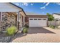 Charming home featuring stone accents, siding, and a brick driveway to the attached two car garage at 4955 N Picadilly Ct, Aurora, CO 80019