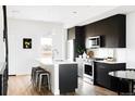 Modern kitchen with black cabinetry, stainless steel appliances, and a center island with seating at 1168 S Reed Way, Lakewood, CO 80232