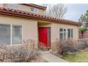 Close-up on the front door with a red door, storm door, and desert landscaping at 4543 S Auckland Ct, Aurora, CO 80015