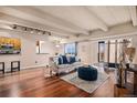 Bright living room featuring hardwood floors, exposed beams, a plush sofa, and access to a balcony at 7865 E Mississippi Ave # 1102, Denver, CO 80247