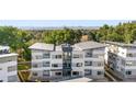 An aerial view shows the modern condo buildings surrounded by lush trees, neighborhood and mountain views at 1308 Snowberry Ln # 303, Louisville, CO 80027