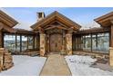 Grand entryway with stone pillars, exposed beams, double doors, and views through picture windows at 300 Little Sallie Barber Trl, Breckenridge, CO 80424