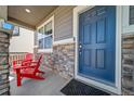 Cozy front porch with stone accents, a blue front door, a doormat, and two red Adirondack chairs at 17382 Bluetrail Ave, Parker, CO 80134