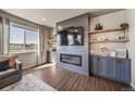 Modern living room with a large window, an electric fireplace, built-in shelves, and hardwood floors at 17382 Bluetrail Ave, Parker, CO 80134