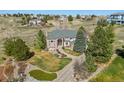Aerial view of a brick home with mature trees, a driveway, and manicured landscaping at 19281 E Hinsdale Ln, Centennial, CO 80016