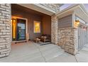 Inviting front porch with cozy seating area, stone columns, and a 'Welcome Home' sign at 9388 Dunraven Loop, Arvada, CO 80007