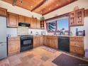 Spacious kitchen featuring custom cabinets, black appliances, and a cozy atmosphere at 13012 S Wamblee Valley Rd, Conifer, CO 80433