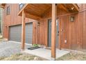 A covered entryway leads to a wood paneled home with a large 2-car garage, lit by exterior wall sconces at 79 Beaver Rd, Idaho Springs, CO 80452
