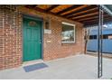 Inviting front porch with a green door, brick facade, and tiled floor, offering a charming entry at 3242 N Albion St, Denver, CO 80207