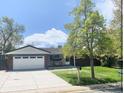 Inviting single-Gathering home featuring a lush green lawn, brick facade, and an attached two-car garage at 13024 E Alaska Pl, Aurora, CO 80012
