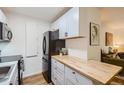 Bright kitchen with butcher block counters, white cabinetry, and modern stainless steel appliances at 5995 E Iliff Ave # 106, Denver, CO 80222