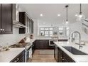 Modern kitchen with stainless steel appliances, white countertops, dark cabinets, and a tiled backsplash at 11027 Sunshimmer Cir, Parker, CO 80134