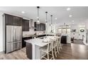 Open-concept kitchen with stainless steel refrigerator, kitchen island and dark wood cabinets at 11027 Sunshimmer Cir, Parker, CO 80134