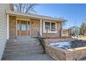 Inviting brick home featuring a stylish wooden front door with decorative glass and well-maintained landscaping at 5927 S Kline St, Littleton, CO 80127