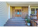 Inviting brick home featuring a stylish wooden front door with decorative glass and well-maintained landscaping at 5927 S Kline St, Littleton, CO 80127