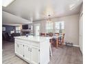 Open-concept kitchen with white cabinets and island, flows seamlessly into the dining and living spaces at 10961 Main Range Trl, Littleton, CO 80127