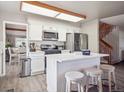 Modern kitchen boasts stainless appliances, white cabinets and island seating, adjacent to staircase at 10961 Main Range Trl, Littleton, CO 80127