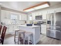 Bright kitchen featuring white cabinets, stainless steel appliances, and a convenient center island with bar seating at 10961 Main Range Trl, Littleton, CO 80127