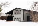 Gray house with black accents, covered carport, and snowy yard at 860 S Quivas St, Denver, CO 80223