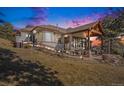 Serene backyard featuring a covered patio, outdoor seating, lush lawn, and picturesque mountain views at 32569 El Diente Ct, Evergreen, CO 80439