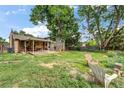 Enjoy this home's expansive backyard, featuring a covered patio ideal for entertaining, surrounded by mature trees at 1161 S Johnson Way, Lakewood, CO 80232