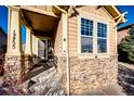 Inviting front porch with stonework and a charming bench at 17725 E 99Th Ave, Commerce City, CO 80022