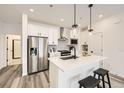 Modern kitchen with white cabinets, stainless steel appliances, an island with bar stools, and wood flooring at 348 N Geneva St, Aurora, CO 80010