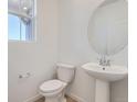 Elegant half bathroom with a pedestal sink, stylish mirror, and modern fixtures in a well-lit space at 11008 Snowdon St, Parker, CO 80134