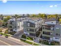An aerial view showcases a modern townhome community with lush landscaping and scenic mountain views at 1615 Harlan St # 2, Lakewood, CO 80214