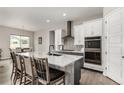 Modern kitchen features a large island with seating and white cabinets with stainless steel appliances at 5839 Hay Market Trl, Parker, CO 80134