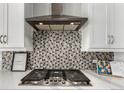Kitchen featuring a stainless steel range hood, modern backsplash, white cabinets, and quartz countertops at 5839 Hay Market Trl, Parker, CO 80134