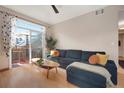 Cozy living room with a plush blue sofa, hardwood floors, and a sliding door to a private balcony at 8500 E Jefferson Ave # 11C, Denver, CO 80237