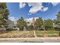 Charming townhouse exterior with lush landscaping, a brick chimney, and beautiful trees creating a serene setting at 180 S Nome St, Aurora, CO 80012