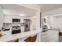 Modern kitchen with white cabinetry, stainless steel appliances, marble backsplash, and an adjacent breakfast bar at 180 S Nome St, Aurora, CO 80012