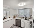 Bright, functional kitchen with stainless steel dishwasher, marble countertops, and ample cabinet space by the sink at 180 S Nome St, Aurora, CO 80012