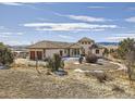 Expansive stucco house with a circular driveway and beautiful views, set in a natural landscape at 8611 Coachlight Way, Littleton, CO 80125