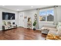 Comfortable living room with hardwood floors, a cozy couch, decor shelving, and a large TV at 1010 S Osceola St, Denver, CO 80219