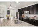 Charming kitchen featuring stainless steel appliances, granite countertops and dark wood cabinets at 9080 Fig St, Arvada, CO 80005