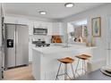 Well-lit kitchen with stainless steel appliances, white cabinets, breakfast bar, and modern fixtures at 9658 W Chatfield Ave # D, Littleton, CO 80128