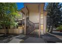 Two-story condo with a covered deck entrance, brown trim, complemented by lush trees and shrubbery at 1111 S Garrison St # 202, Lakewood, CO 80232
