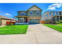 Charming two-story home with a covered porch, stone accents, a well-manicured lawn, and a wide concrete driveway at 7888 E 139Th Pl, Brighton, CO 80602