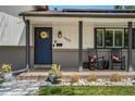 Cozy front porch with rocking chairs and a charming sunflower wreath on the door at 6439 E Maplewood Ave, Centennial, CO 80111