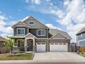 Two story home with a stone accents, three car garage, a covered porch, and manicured lawn at 8346 E 132Nd Dr, Thornton, CO 80602