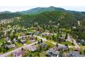 A serene aerial view of a neighborhood nestled among lush green trees and rolling mountains at 3257 Sun Ridge Ln, Evergreen, CO 80439