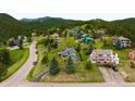 An aerial view of the property nestled among lush greenery with mountain views at 3257 Sun Ridge Ln, Evergreen, CO 80439