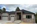 Beautiful single-story home showcasing stone pillars, gray siding, and a three-car garage at 6152 Powell Rd, Parker, CO 80134