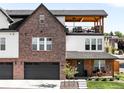 A brick-front home with a garage, covered porch, upper deck, and well-maintained landscaping at 8357 W 68Th Ln, Arvada, CO 80004
